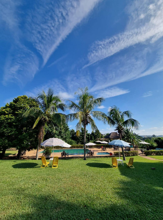 Área verde com piscina ao fundo e céu azul